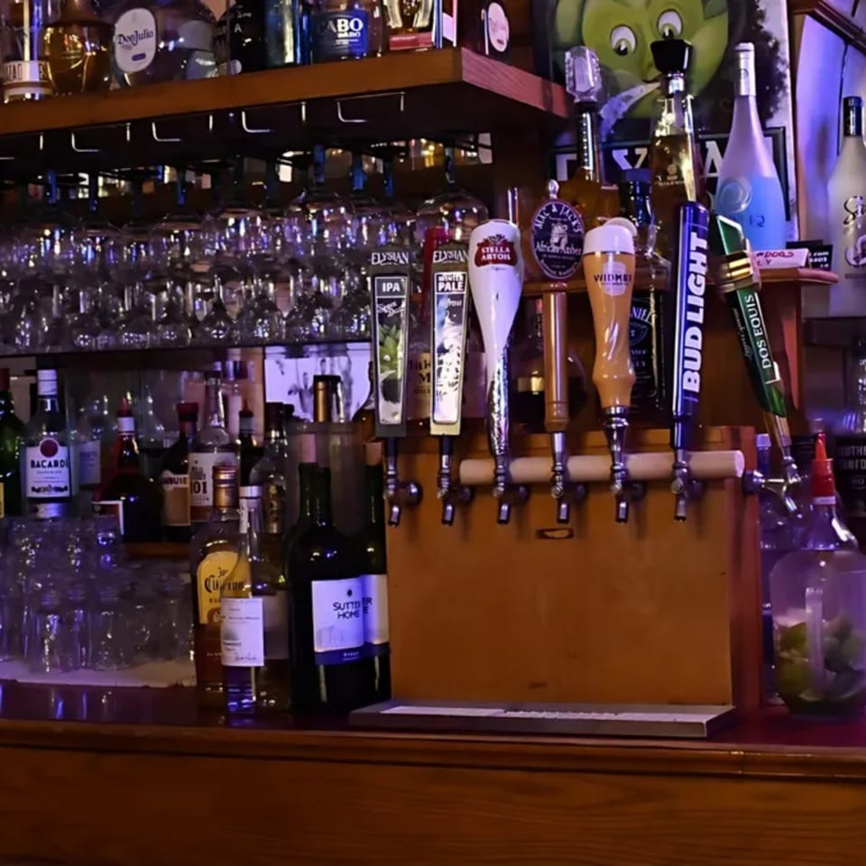 A well-stocked bar at Puerto Vallarta West Seattle, featuring various liquor bottles, beer taps, and glassware.