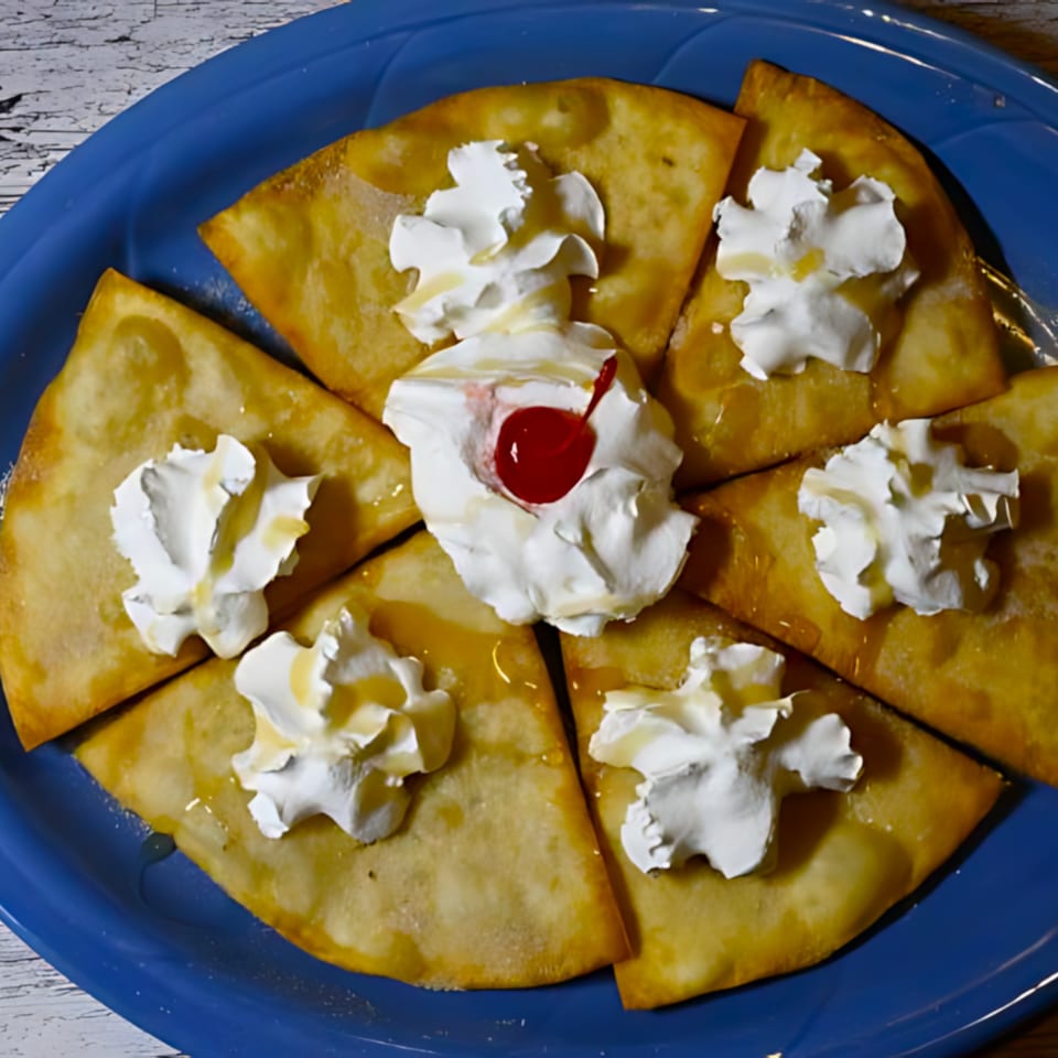 Golden fried tortilla wedges, drizzled with honey, topped with whipped cream and a cherry.